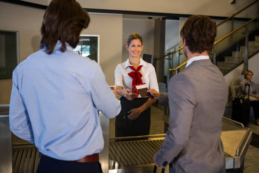 Imagen de una recepcionista atendiendo a dos huéspedes de un hotel.